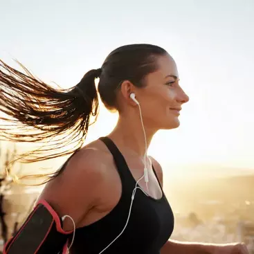 A person running in nature wearing earphones to listen to music.