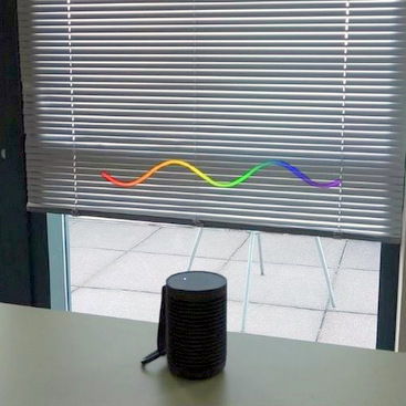 A speaker kept on a table with an AR visualization shown at the top in the form of a green retro volume bar.