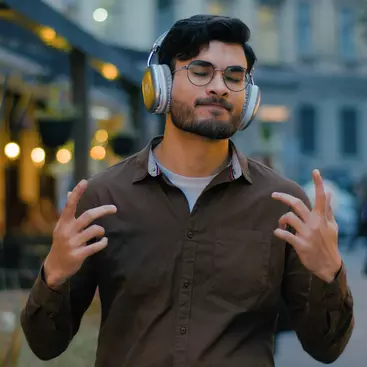 A handsome person listening to music through headphones and humming along.